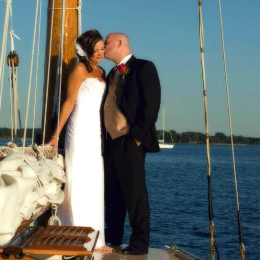 Celebrate love and adventure with Sail Selina, the ideal location for nautical themed weddings and elopements in St. Michaels, MD - This captivating image showcases the loving tenderness between newlyweds as they embark on an unforgettable journey on their boat wedding day - Start your adventure now aboard Sail Selina!