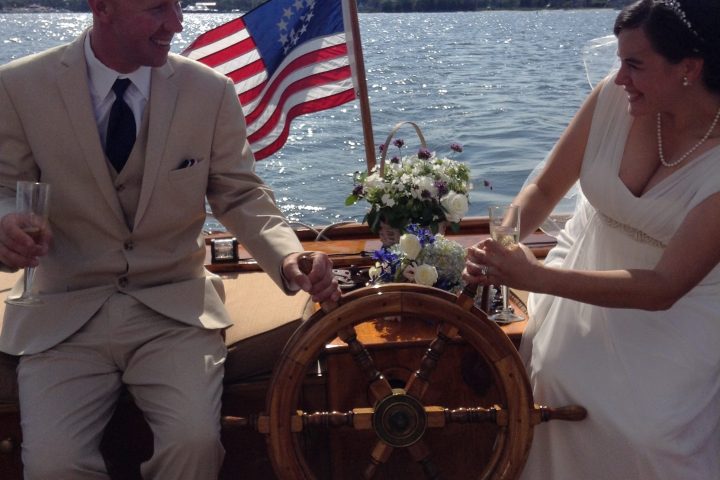 Find the ultimate expression of your love on Sail Selina, the premier venue for nautical themed weddings and elopements in St. Michaels, MD - This playful image features the newlywed couple enjoying the serenity and beauty of their boat wedding day - Book now and make unforgettable memories aboard Sail Selina!