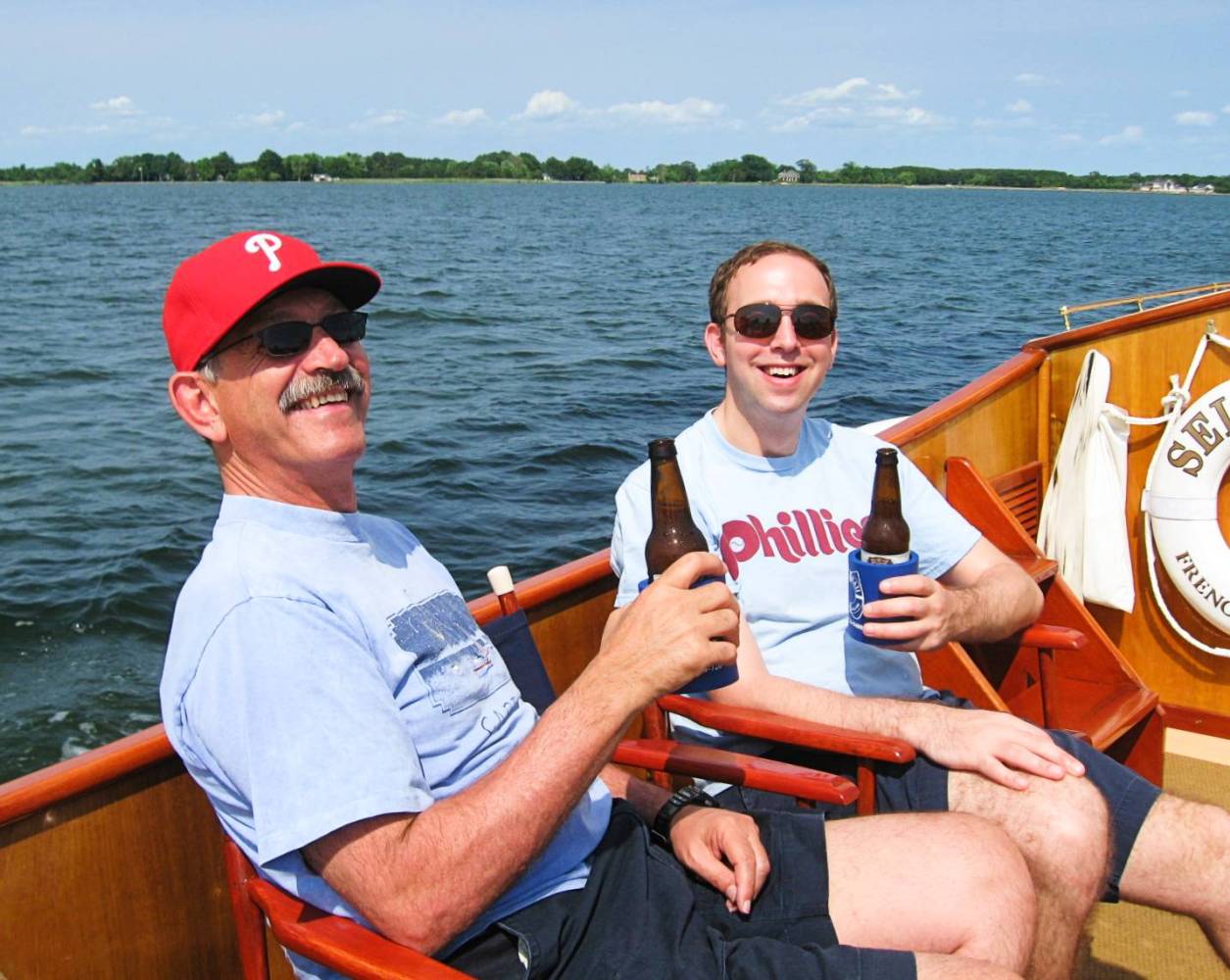 "Indulge in the ultimate sensory adventure with Sail Selina's beer tasting cruises on the Chesapeake Bay in St. Michaels, MD - This fun-filled image showcases a couple of guys cavorting on the boat, tasting delicious brews, and savoring the knowledge of the ship's captain as he regales them with fascinating stories of the Chesapeake Bay and the region's rich history - Book now and join the fun aboard Sail Selina, a one-of-a-kind experience not to be missed