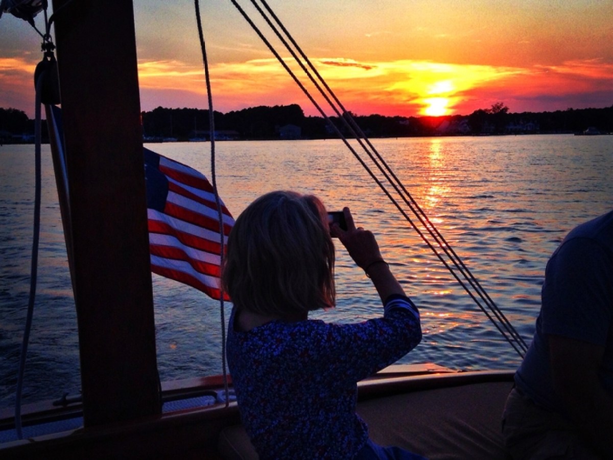 Experience the ultimate sensory adventure with Sail Selina's sunset cruises on the Chesapeake Bay in St. Michaels, MD - This captivating image features a woman gazing off into the enchanting sunset, savoring the serene sights and sounds of the open water - With Sail Selina as your guide, cherish the breathtaking beauty of the bay as you create unforgettable memories - Book now and indulge in the calming and rejuvenating ambiance of a Sail Selina sunset cruise!