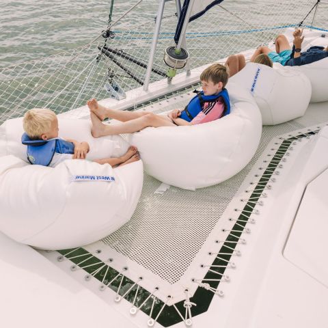 Three people relaxing on bean bags on a boat's deck over water.